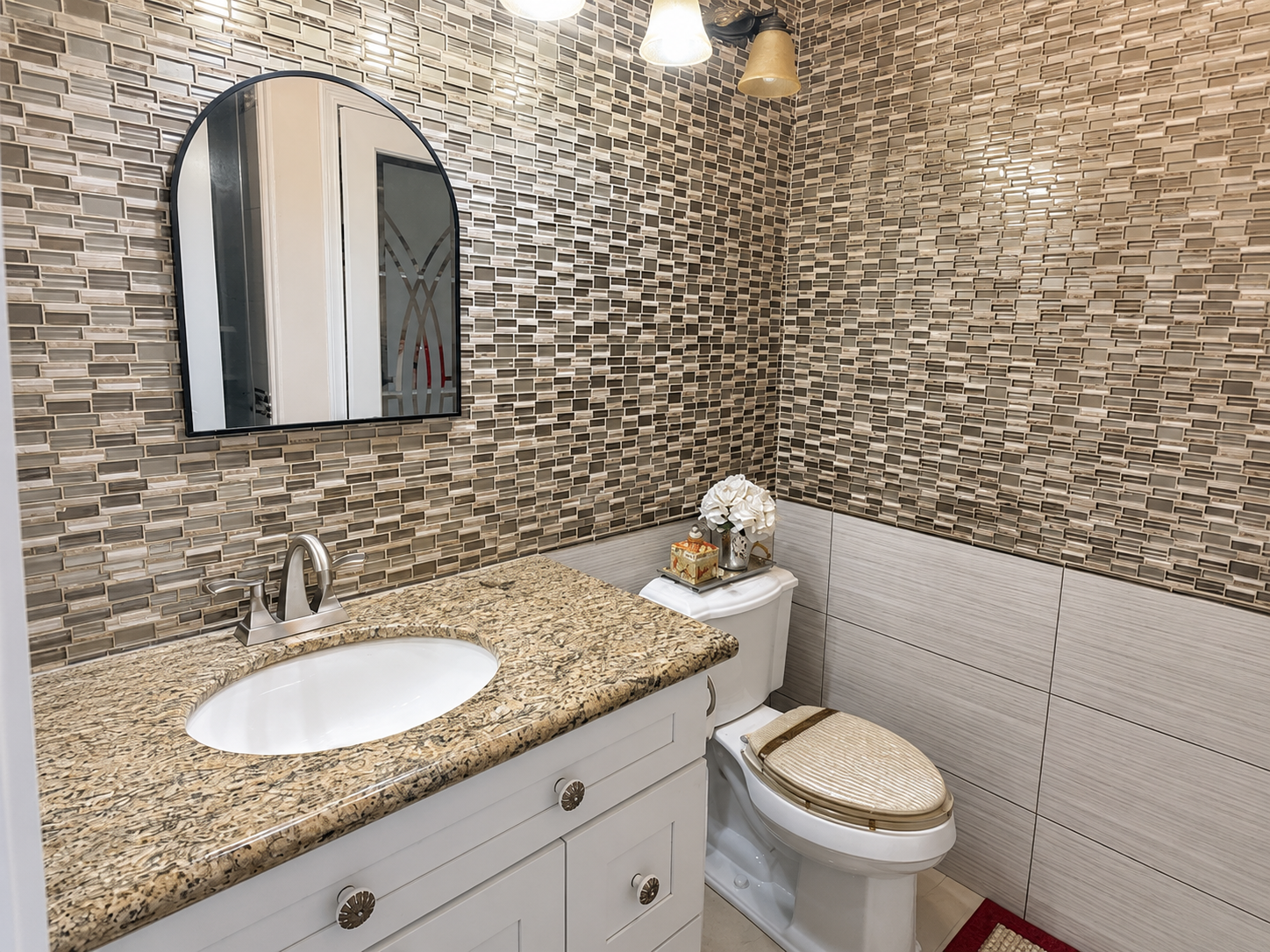 Bath with decorative tile work and arched-mirror vanity