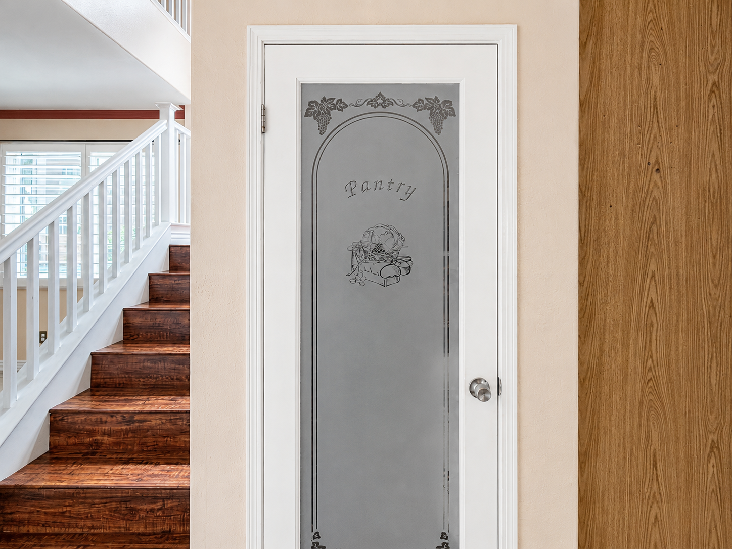 Etched-glass pantry door beside the white-railed staircase