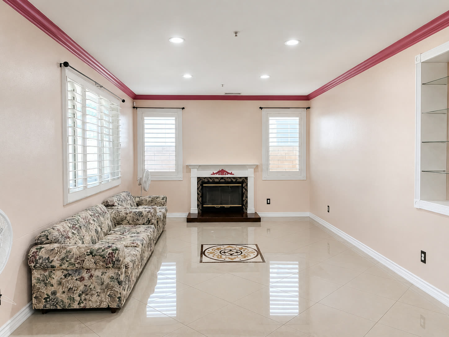 Family room with a wall of shuttered windows and polished tile with an inlay medallion
