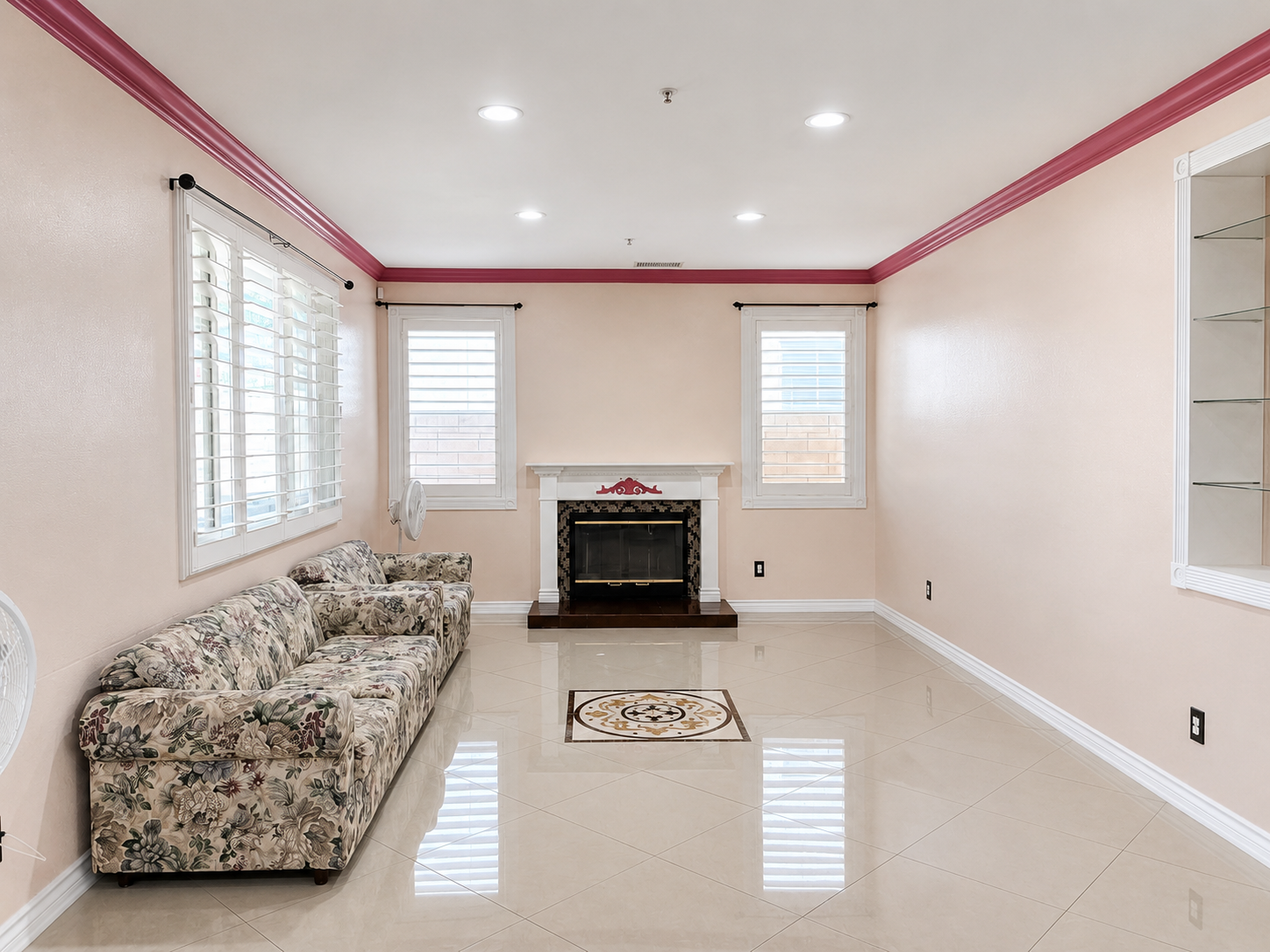 Living room with fireplace, decorative mantel, tile inlay medallion, and plantation-style shutters