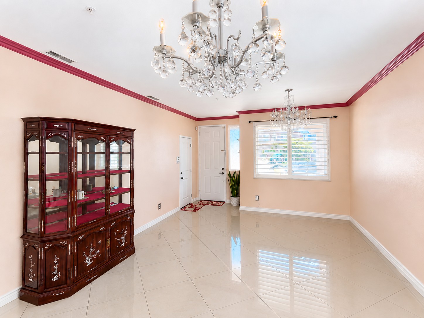 Living room with polished tile floors, crown molding, and two chandeliers