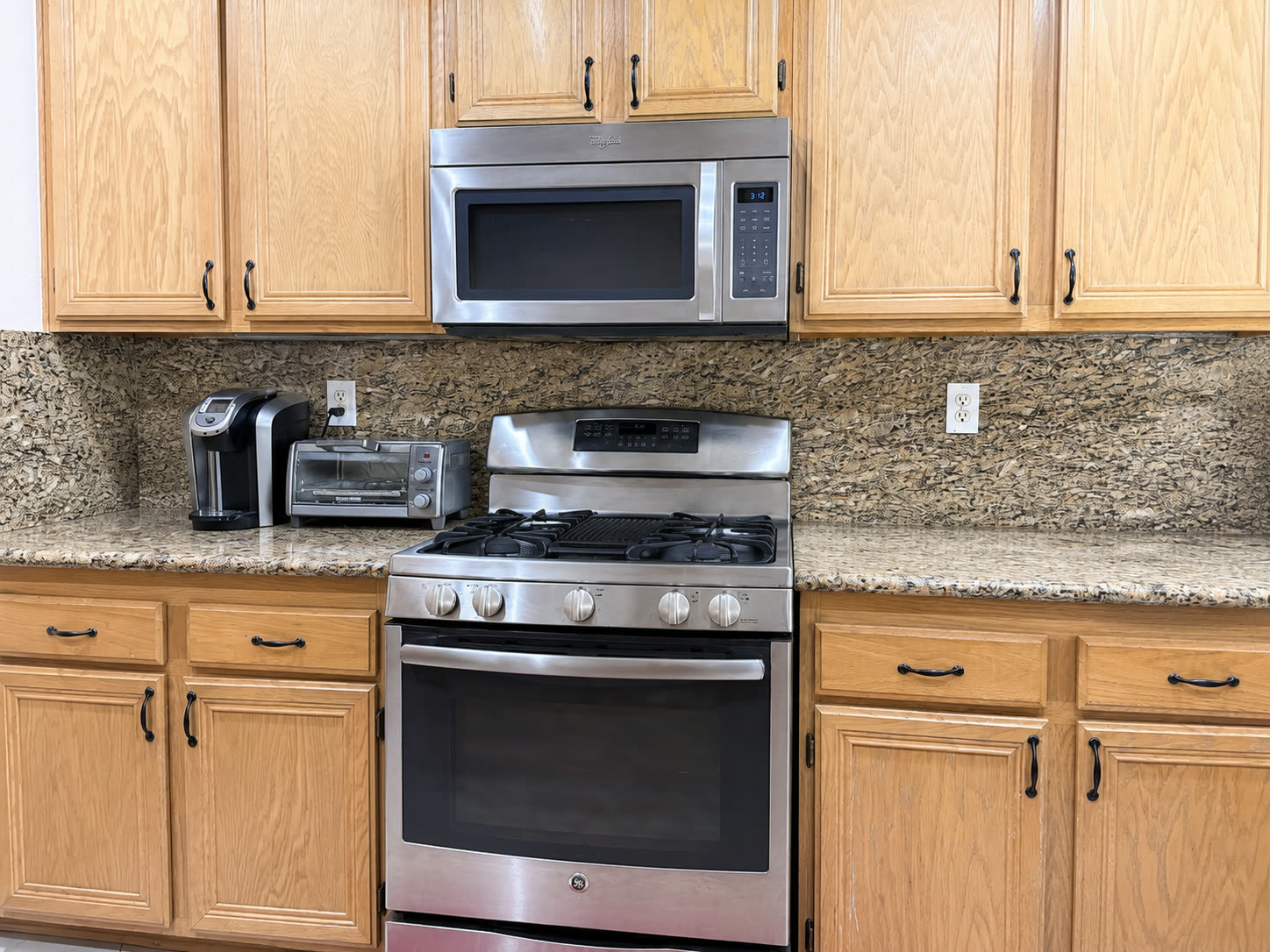 Gas range and stainless appliances against the granite backsplash