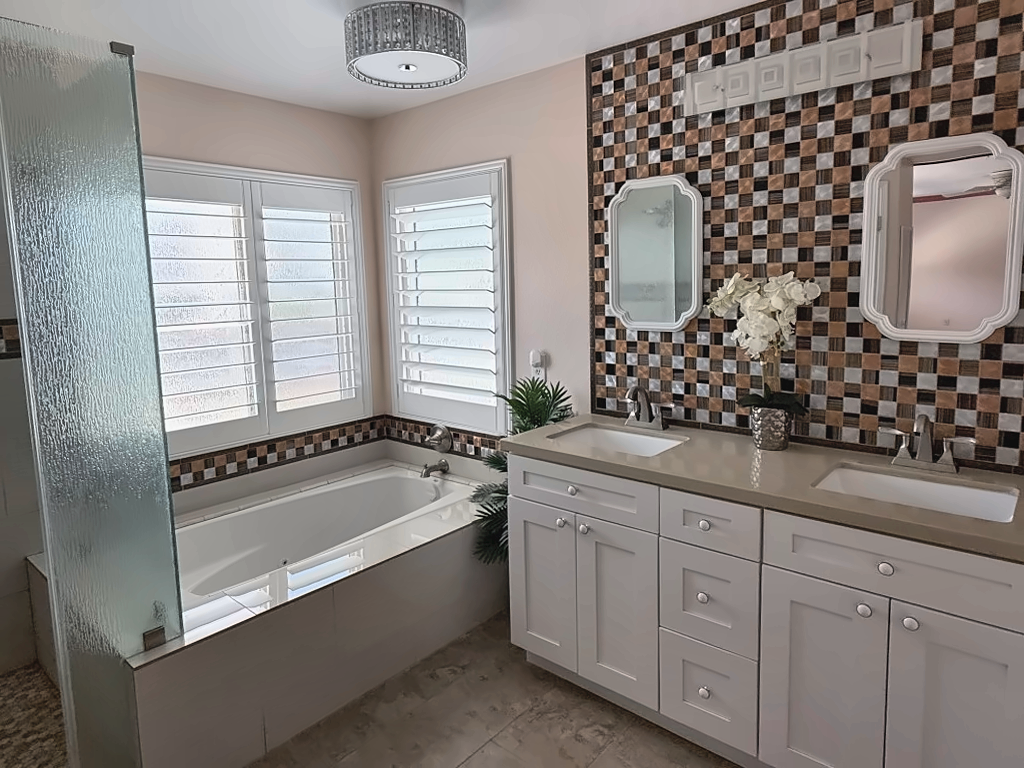 Primary bath with soaking tub, dual-sink vanity, separate glass shower, and mosaic-tile accents
