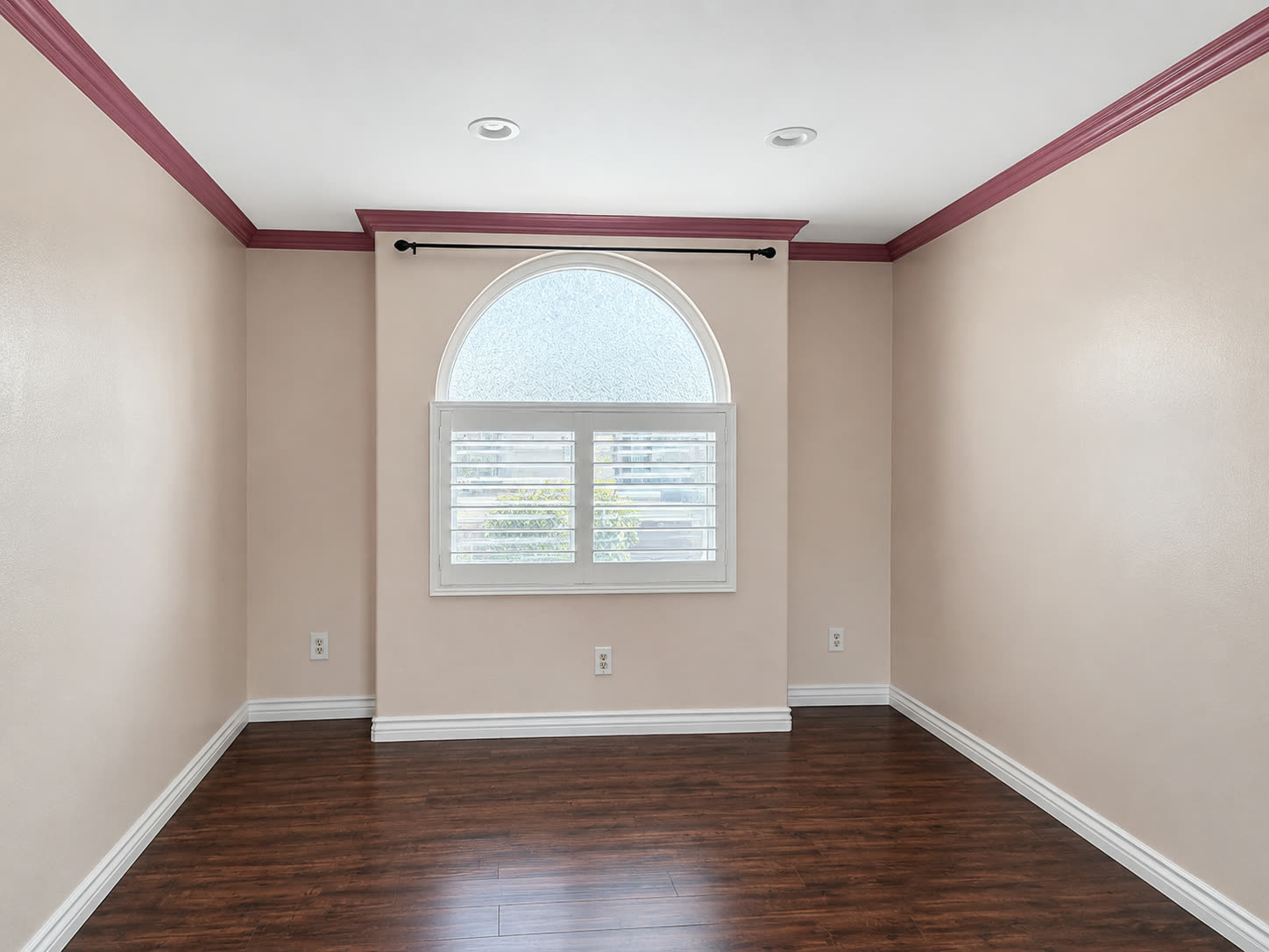 Bedroom with an arched window, shutters, and crown molding