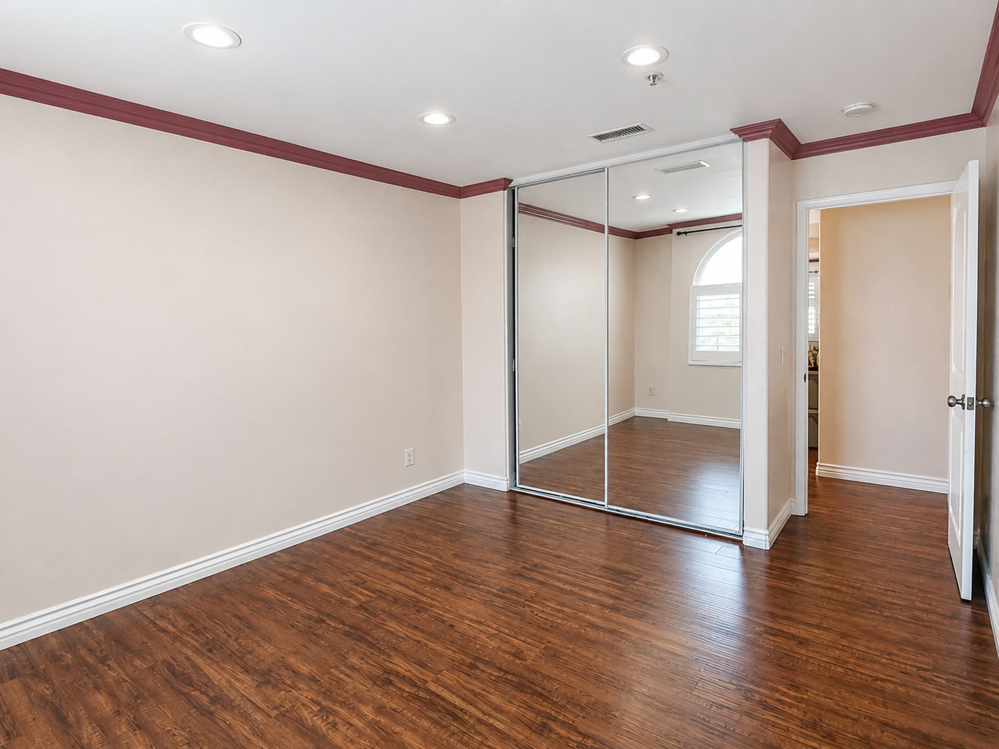 Bedroom with mirrored closet doors and laminate flooring