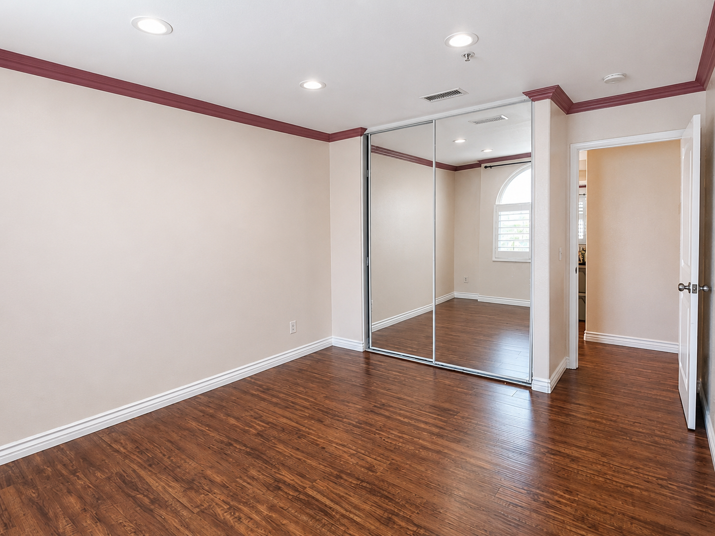 Bedroom with mirrored closet doors and laminate flooring