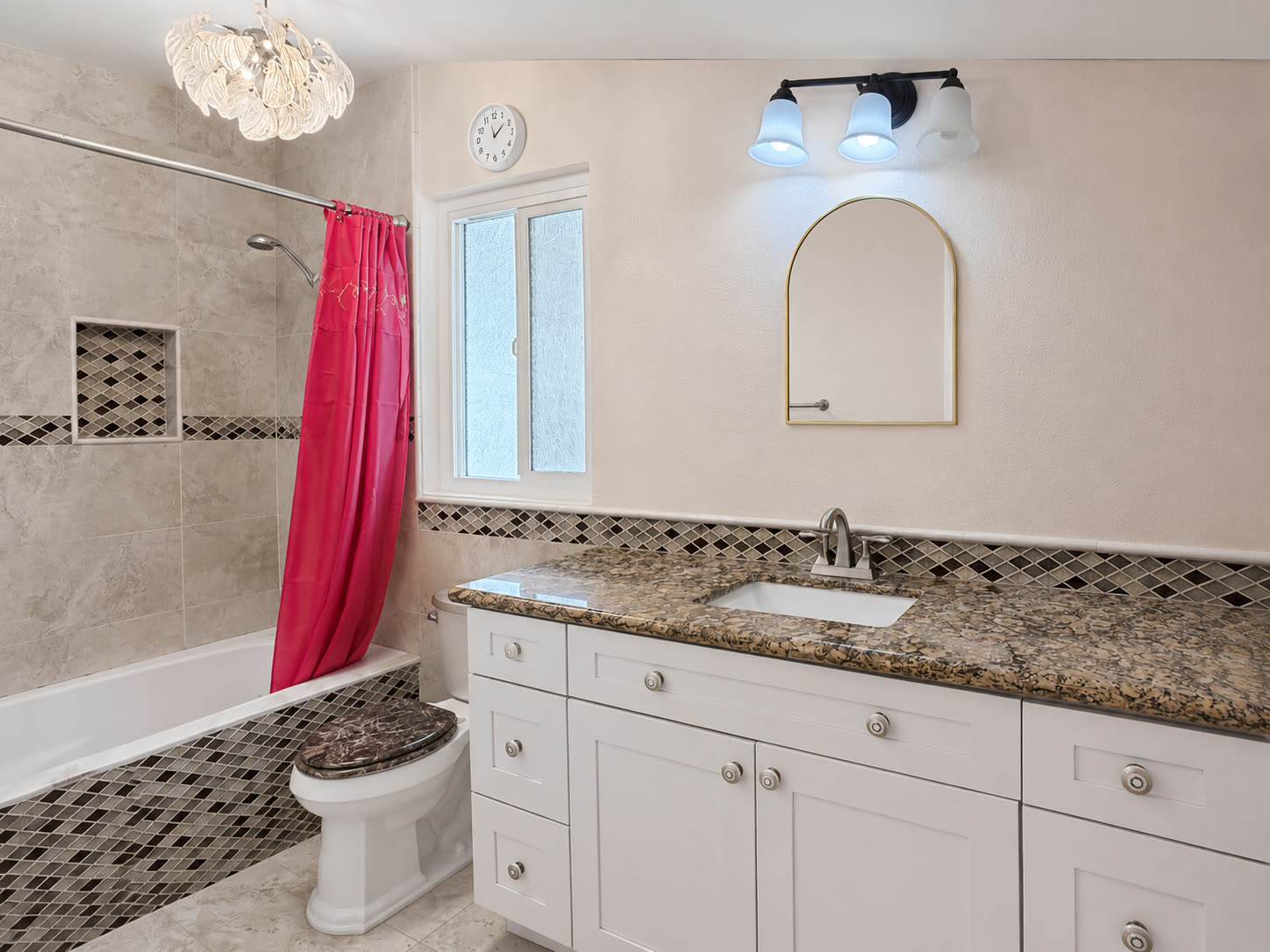 Hall bath with tub and shower, decorative tile surround with niche, and granite-look vanity