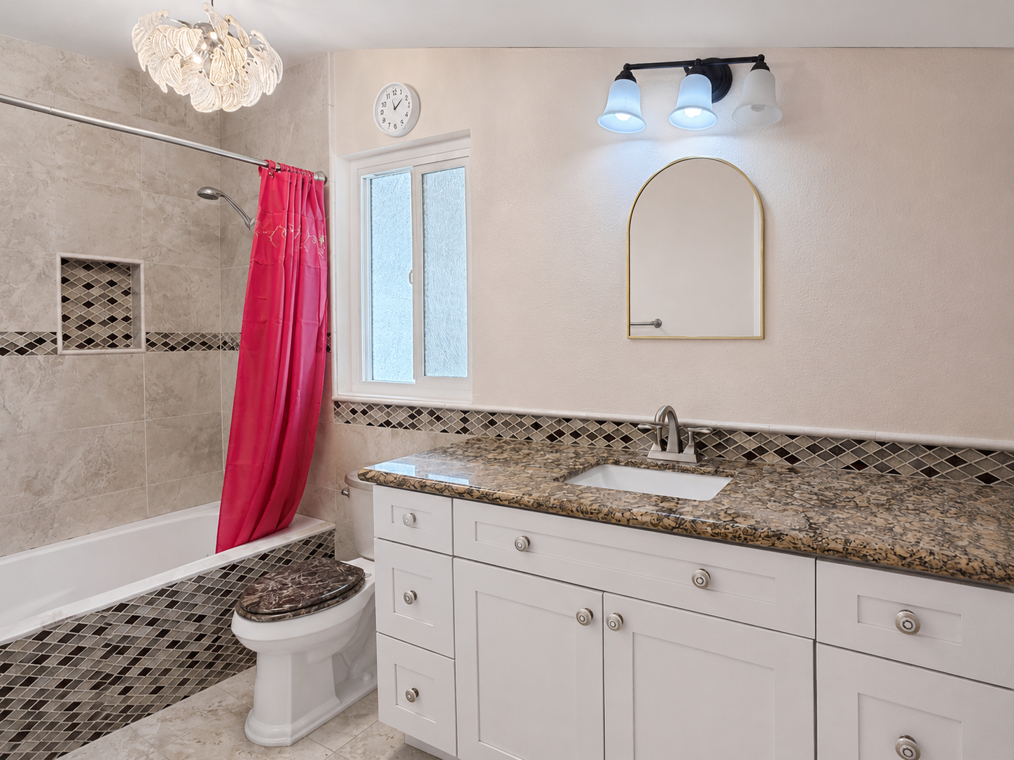 Hall bath with tub and shower, decorative tile surround with niche, and granite-look vanity